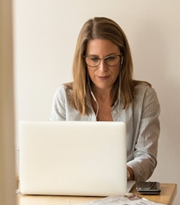 Donna seduta davanti a un computer portatile mentre segue un webinar di Leanus.